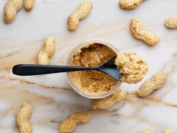 Nut butters: a jar of peanut butter surrounded with whole peanut pods